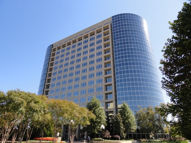 Modern glass office building surrounded by greenery in Atlanta, showcasing the city's urban architecture.