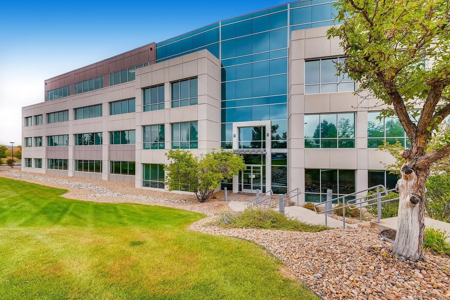 Modern office building in Denver featuring large glass windows and landscaped grounds.
