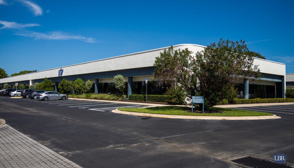 Modern commercial building in Melbourne with landscaped surroundings and a spacious parking lot under a clear blue sky.